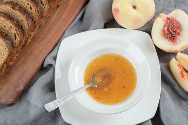 Şeftali reçeli ve kaşıkla dolu beyaz bir tabak