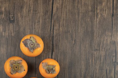 Tahta yüzeye yerleştirilmiş üç olgun hurma meyvesi