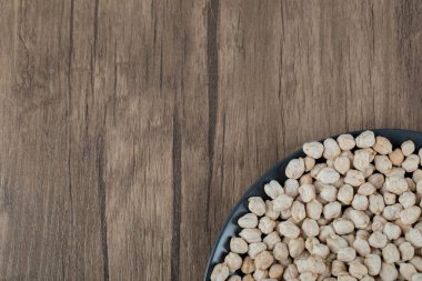 Tahta bir masanın üzerinde kurumuş taze bezelye dolu siyah bir tabak.