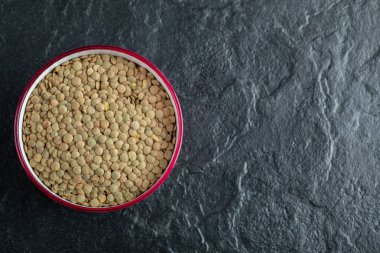 Koyu bir arka planda hazırlıksız mercimek tabağı.