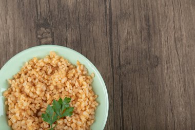 Yeşil tabakta yeşillikleri olan lezzetli bulgur.