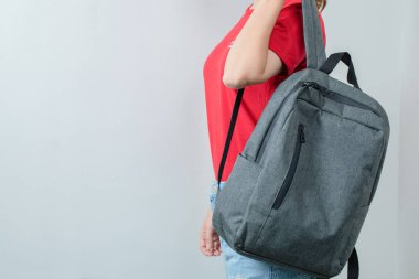 Okul kızı gri sırt çantasını omuzlarına takıyor.