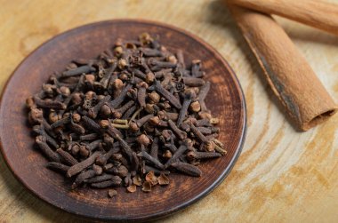 Ahşap bir masada kurumuş karanfil dolu kahverengi bir tabak.