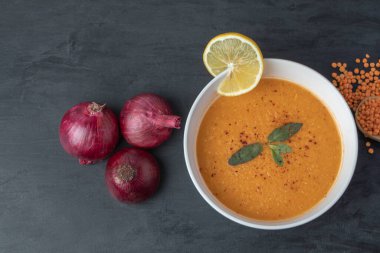 Mercimek çorbası ve soğanlı beyaz bir kase.