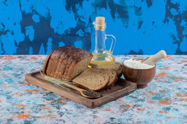 Tahta tabakta yağlı ve unlu kahverengi ekmek dilimleri.