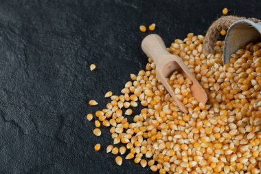Koyu arkaplanda tahta kaşıkla çiğ patlamış mısır.