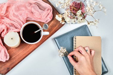 Elinde defterler ve bir kavanoz çiçekle bir çiçek tutarken