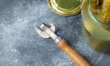 Gri arkaplanda turşu kavanozu ve kavanoz açacağı