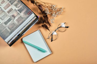 Turuncu arkaplanda kitaplar, defter, kalem ve gözlük