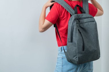 Okul kızı gri sırt çantasını omuzlarına takıyor.