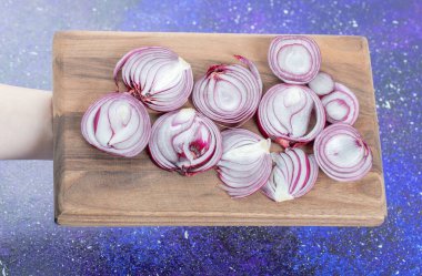 Elin, soğan dilimleriyle tahta kesme tahtasını tutuyor.