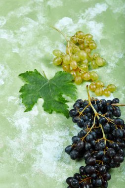 Yeşil arka planda yaprağı olan üzümler.