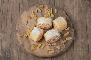 Kuru üzümlü kurabiyeler ve ahşap bir tahtada malzemeler yuvarla.