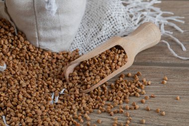 Tahta bir masada çiğ karabuğday dolu tahta bir kaşık.