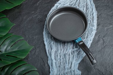 Siyah arka planda mavi tül üzerinde siyah demir tava.