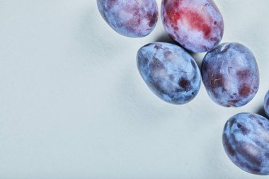 Mavi arka planda bir grup taze erik.