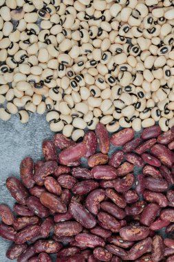 Gri arka planda kurutulmuş beyaz ve kırmızı fasulye.