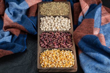 Koyu arkaplanda çiğ fasulye ve patlamış mısır tabakları.