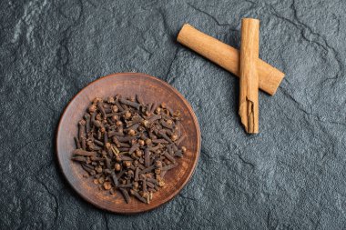Tarçın çubuklu kurumuş karanfil dolu kahverengi bir tabak.