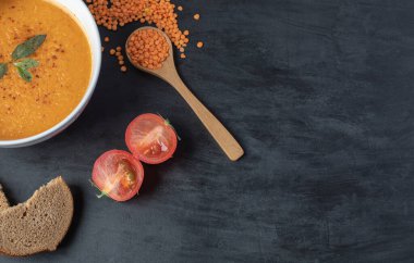 Beyaz bir kase mercimek çorbası ve pişmemiş mercimek fasulyesi.