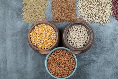 Gri arka planda farklı türde çiğ fasulye.