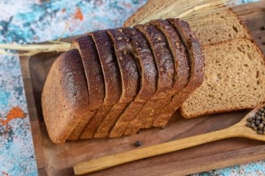 Tahtada taze ekmek dilimleri ve kaşık dolusu biber taneleri.