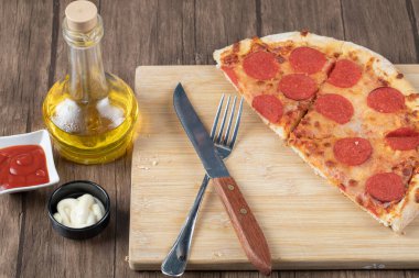 Biberli pizzanın yarısı ahşap tabakta soslu ve yağlı.