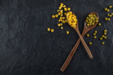 Konserve mısır tohumu ve siyah arkaplanda yeşil zeytin