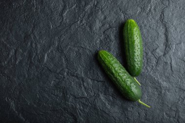 Siyah arka planda taze salatalık ve organik sebzelerin üst görüntüsü.