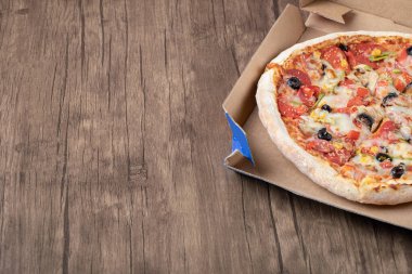 Tahta masanın üzerinde pizza kutusunda sıcak karışık pizza.
