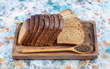 Tahtada siyah ekmek dilimleri ve kaşık dolusu karabiber.