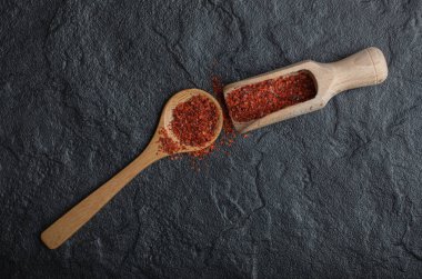 Siyah arka planda iki tahta kaşık kırmızı biber tozu.