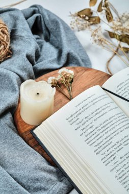 Tahtada mum ve çiçek olan kitap.