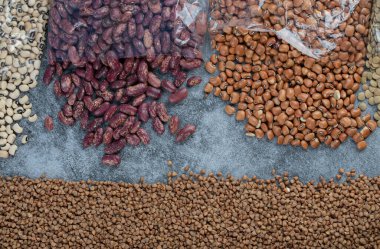 Gri arka planda farklı türde çiğ fasulye.