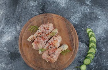 Tahtada çiğ tavuk budu ve taze doğranmış salatalık. Üst görünüm