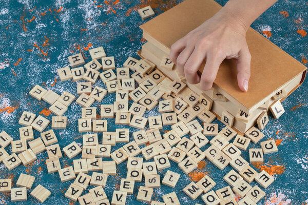Wooden dice with printed letters on them between book pages