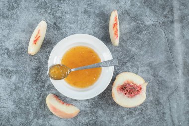 Gri masa örtüsü üzerinde reçelli ve şeftalili beyaz bir tabak