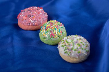 Mavi kumaş üzerinde üç renkli kurabiye.