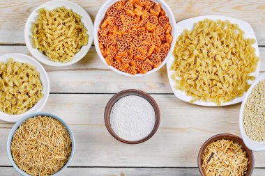 Beyaz ve ahşap kaplar üzerinde un içeren çeşitli çiğ makarna manzarası