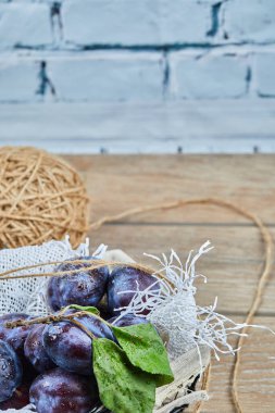 Bahçe erikleri bir sepetin içinde, ahşap bir masada, yakın