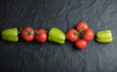 Taze sebze yığınının en üst görüntüsü. Siyah arkaplanda domates ve biber