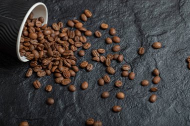 Siyah bir fincanda koyu kahve çekirdekleri.