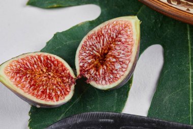 Beyaz arka planda dilimlenmiş siyah incir ve yaprak.