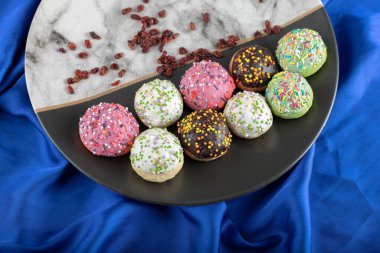 Mavi kumaş üzerine serpiştirilmiş renkli kurabiyeler.