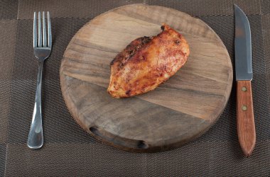 Kızarmış tavuk göğsü olan tahta bir tahta.