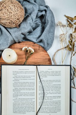 Beyaz arka planda mum ve kurumuş çiçeklerle kaplı kitabı aç