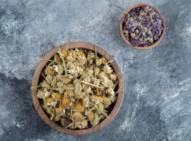 Kurumuş mor çiçekler ve tahta kaselerde papatyalar.