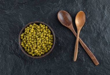 İki ahşap kaşık ve bir kase dolusu yeşil zeytin.