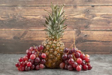 Olgun ananaslı taze kırmızı üzümler mermer yüzeyde
