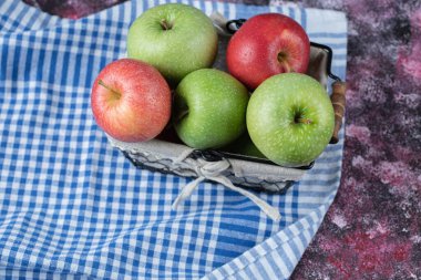 Beyaz havluyla sepette elmalar.